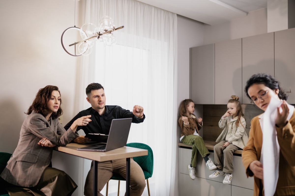 Parents reviewing paperwork at the kitchen table while their children play nearby