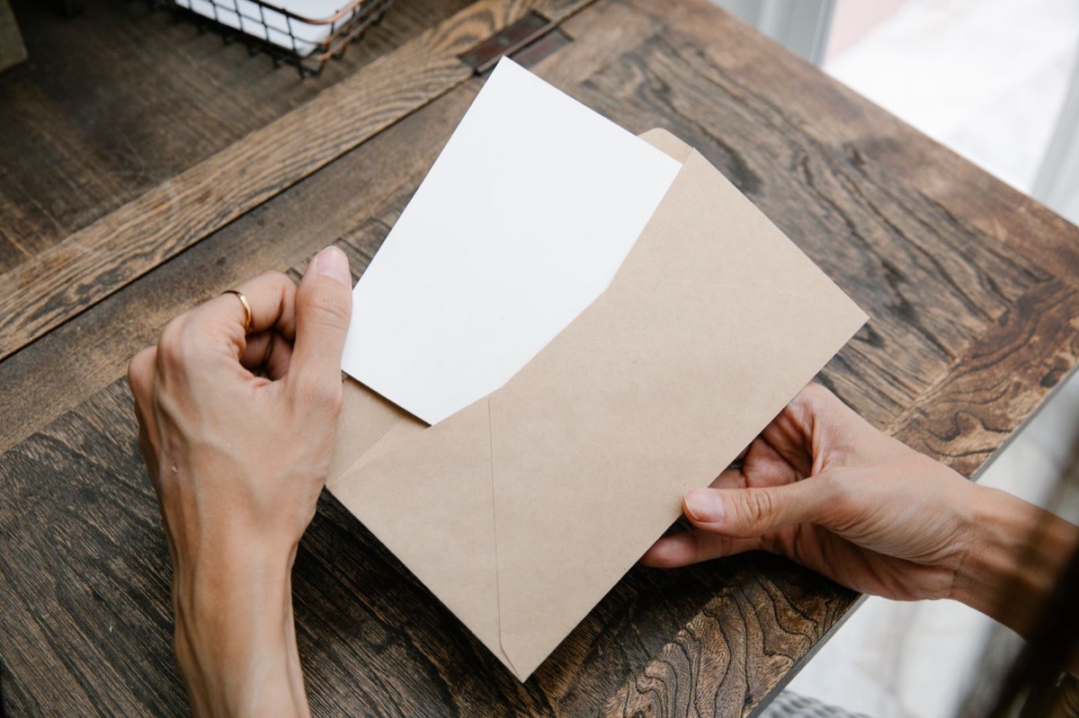 Hands opening an envelope with a letter inside
