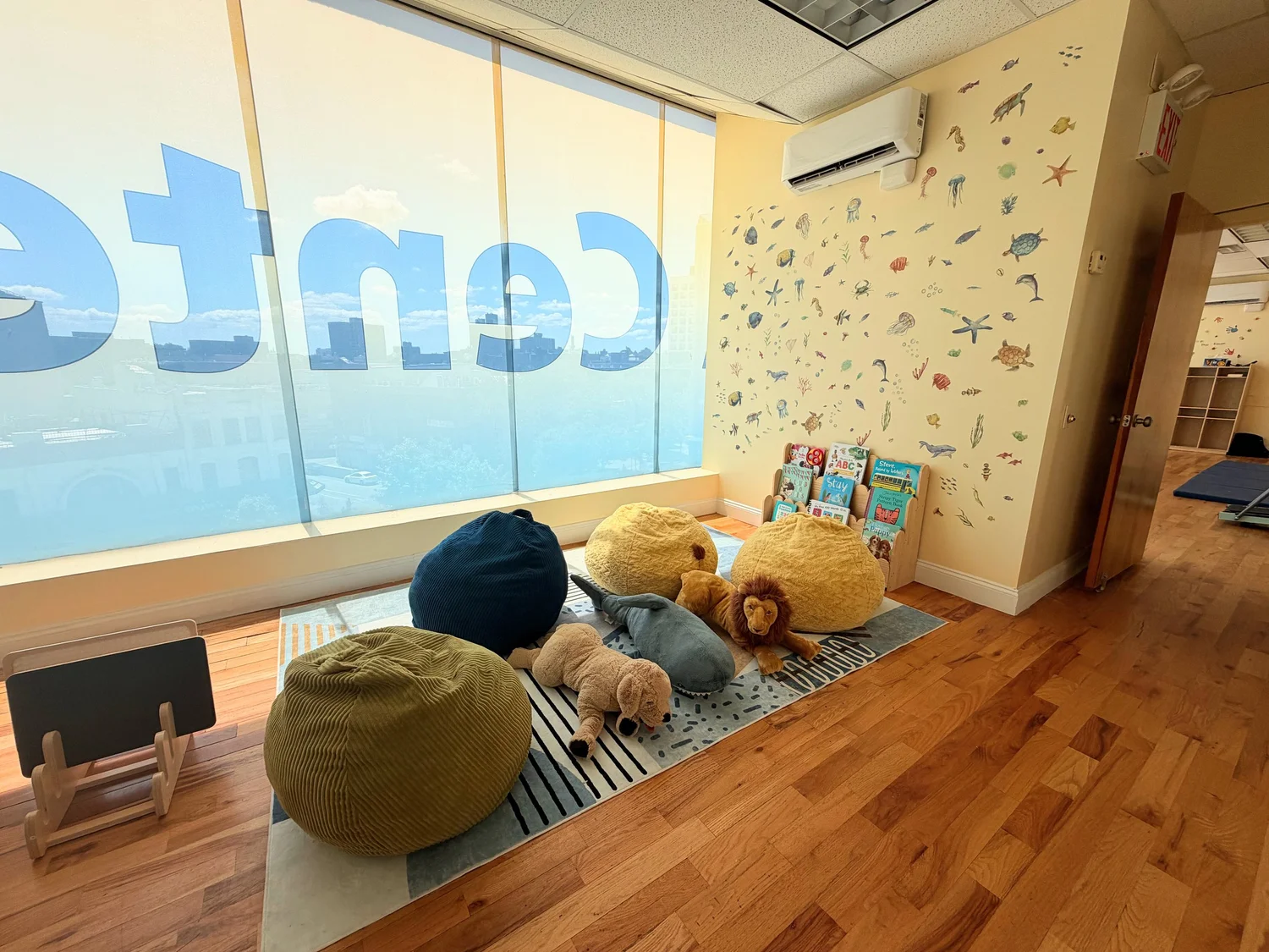 Cozy children's reading area with sea-creature wall decals and a bookshelf by large windows