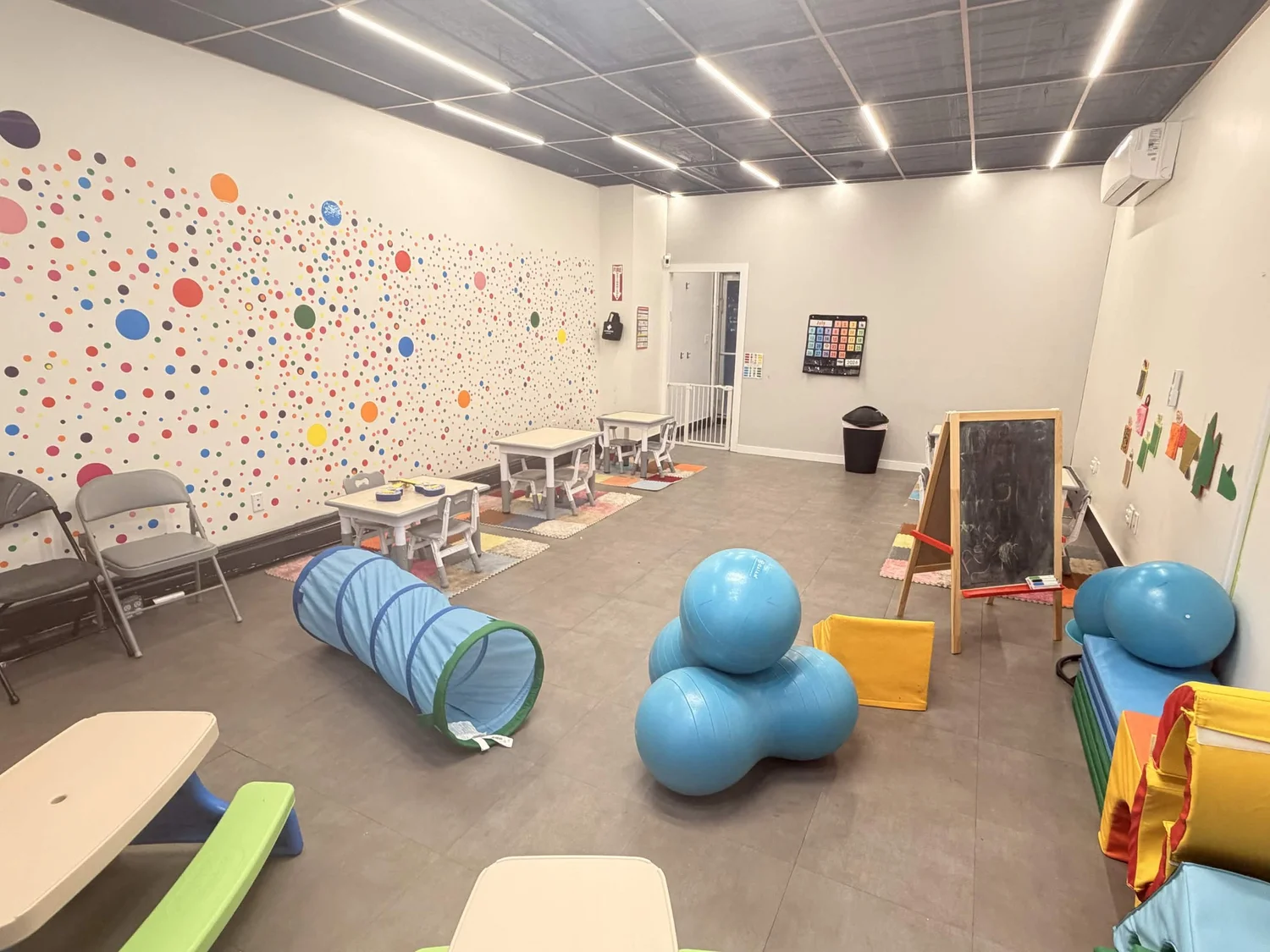 Colorful sensory-friendly playroom with play mats, toys, and educational wall decorations at the Brooklyn Center