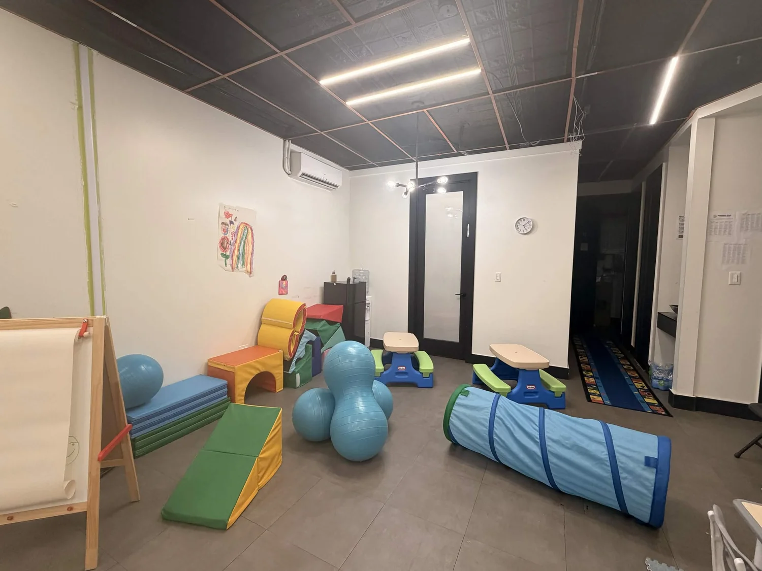 Play area with soft mats, a crawl tunnel, and exercise balls